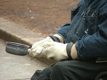 Midsection of person holding container on footpath