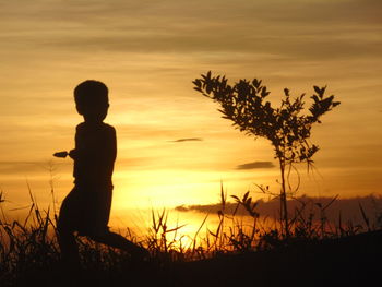 Silhouette woman standing at beach during sunset