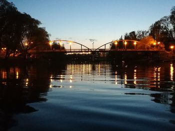 Illuminated bridge over river against sky at dusk