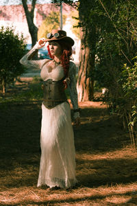 Full length of young woman in dress standing on grassy field