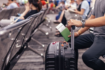 Midsection of man with luggage sitting at airport