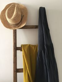 Close-up of hat hanging on ladder against wall at home