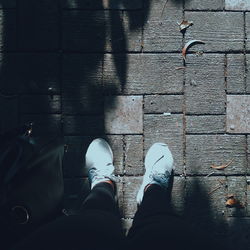 Low section of woman standing by purse on footpath