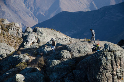 People on rocks against mountains
