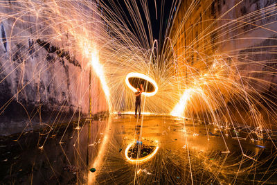 Man spinning wire wool while standing on street at night