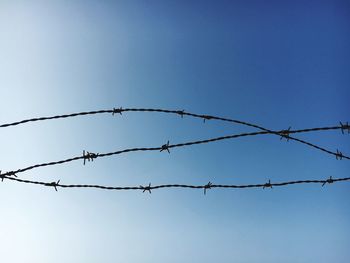 Barbed wire against clear blue sky