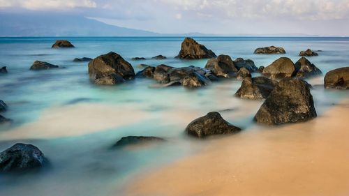 Rocks in sea against sky