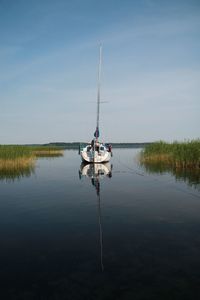 Sailboat on lake against sky during sunny day