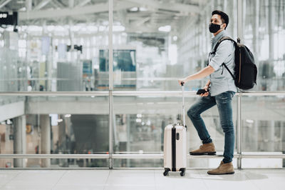 Man wearing mask with luggage waiting at airport