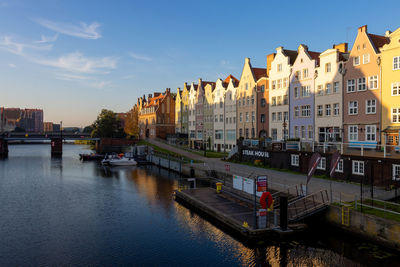 Buildings by river against sky in city
