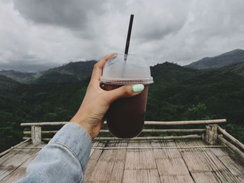 Midsection of person holding umbrella against mountain