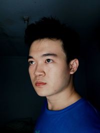Close up portrait of young handsome asian male wears casual blue shirt against black background