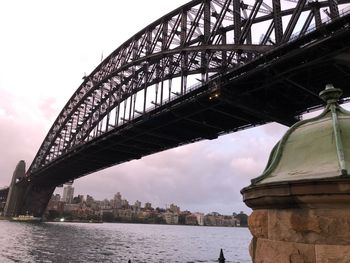 Low angle view of bridge over river against sky in city