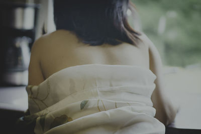 Rear view of woman sitting on bed