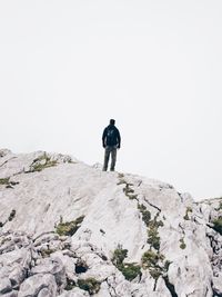 Rear view of man walking on mountain against clear sky