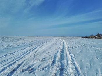 Snow covered landscape against blue sky