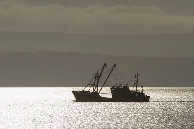 Silhouette sailboat in sea against sky