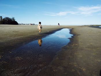 Boy reflecting in water at beach
