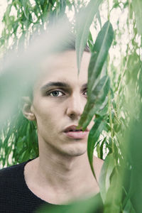 Close-up portrait of young woman against plants