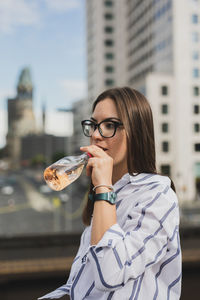 Portrait of young woman drinking sunglasses