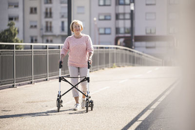 Senior woman with wheeled walker on footbridge