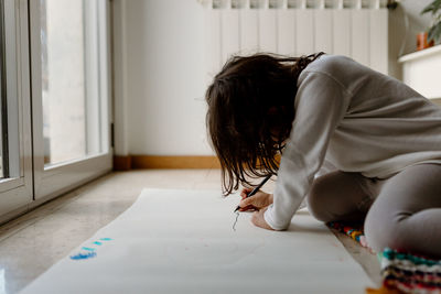 Rear view of girl drawing on table