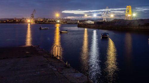 Illuminated bridge over river against sky at night