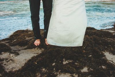 Low section of man standing on beach