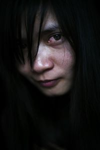 Portrait of young woman against black background