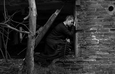 Sad woman crouching on abandoned window