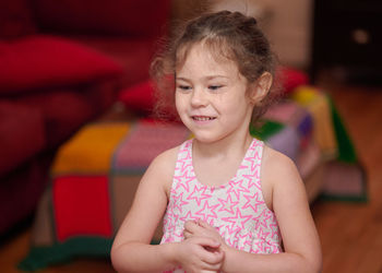 Portrait of a young girl in the livingroom at home making faces and signs of the camera