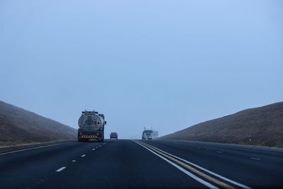 Road leading towards mountains against blue sky