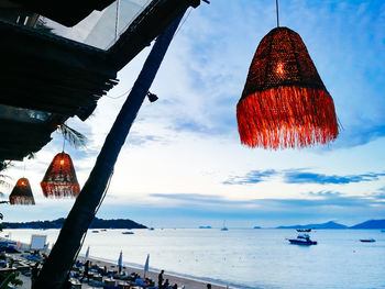 Low angle view of lanterns hanging by sea against sky