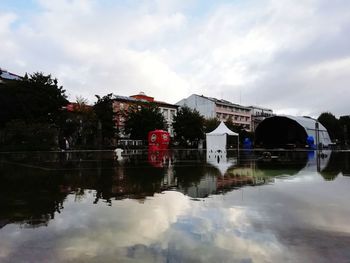 Buildings by lake against sky