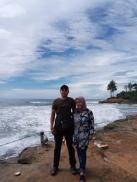 Full length of friends standing on beach against sky