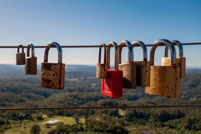 Padlocks hanging on railing against sky