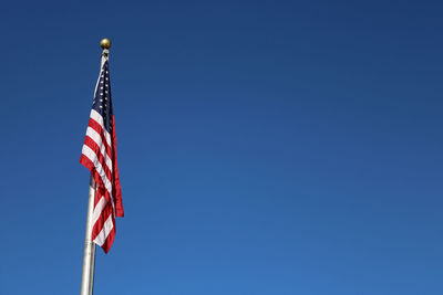 Low angle view of flag against clear blue sky