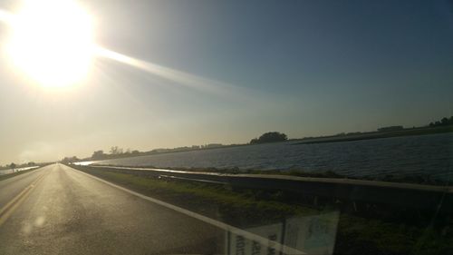 Road by sea against clear sky during sunset