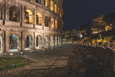 Footpath amidst buildings in city at night