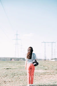 Rear view of woman standing on field against sky