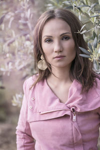 Close-up portrait of young woman standing against tree