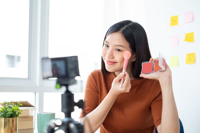 Portrait of smiling woman holding mobile phone