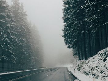 Road amidst snow covered trees against sky