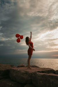 Full length of man standing on rock at beach against sky
