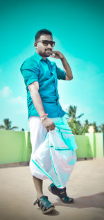 Full length of man standing against blue wall