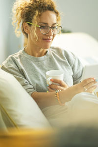 Portrait of young woman sitting on bed at home