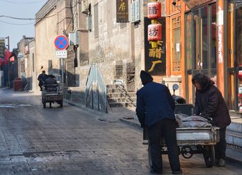 Rear view of people on street against buildings in city