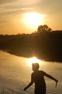 Silhouette man on shore against sky during sunset