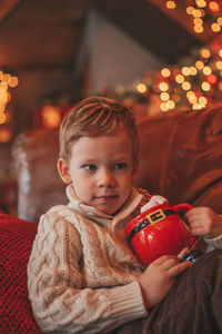 Portrait candid happy kid in knit beige sweater hold xmas mug with marshmallows and candy cane