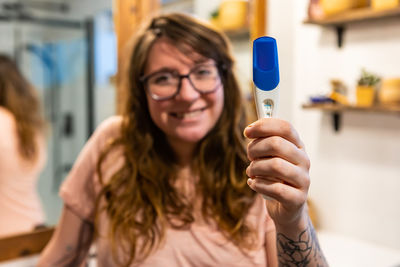 Portrait of smiling woman holding pregnancy test kit